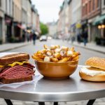 Montreal street food lineup featuring a smoked meat sandwich, poutine in a bowl, and a toasted bagel with cream cheese on a sidewalk table.